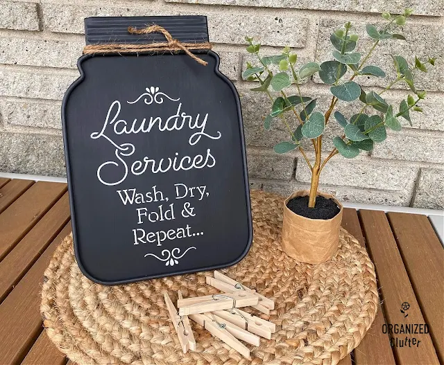 Photo of a jar shaped metal chalkboard with easel repurposed into a fun farmhouse laundry room sign.