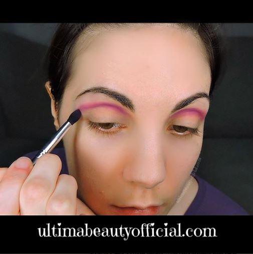 Ultima Beauty applying violet eyeshadow to the crease of the eye with a blending brush