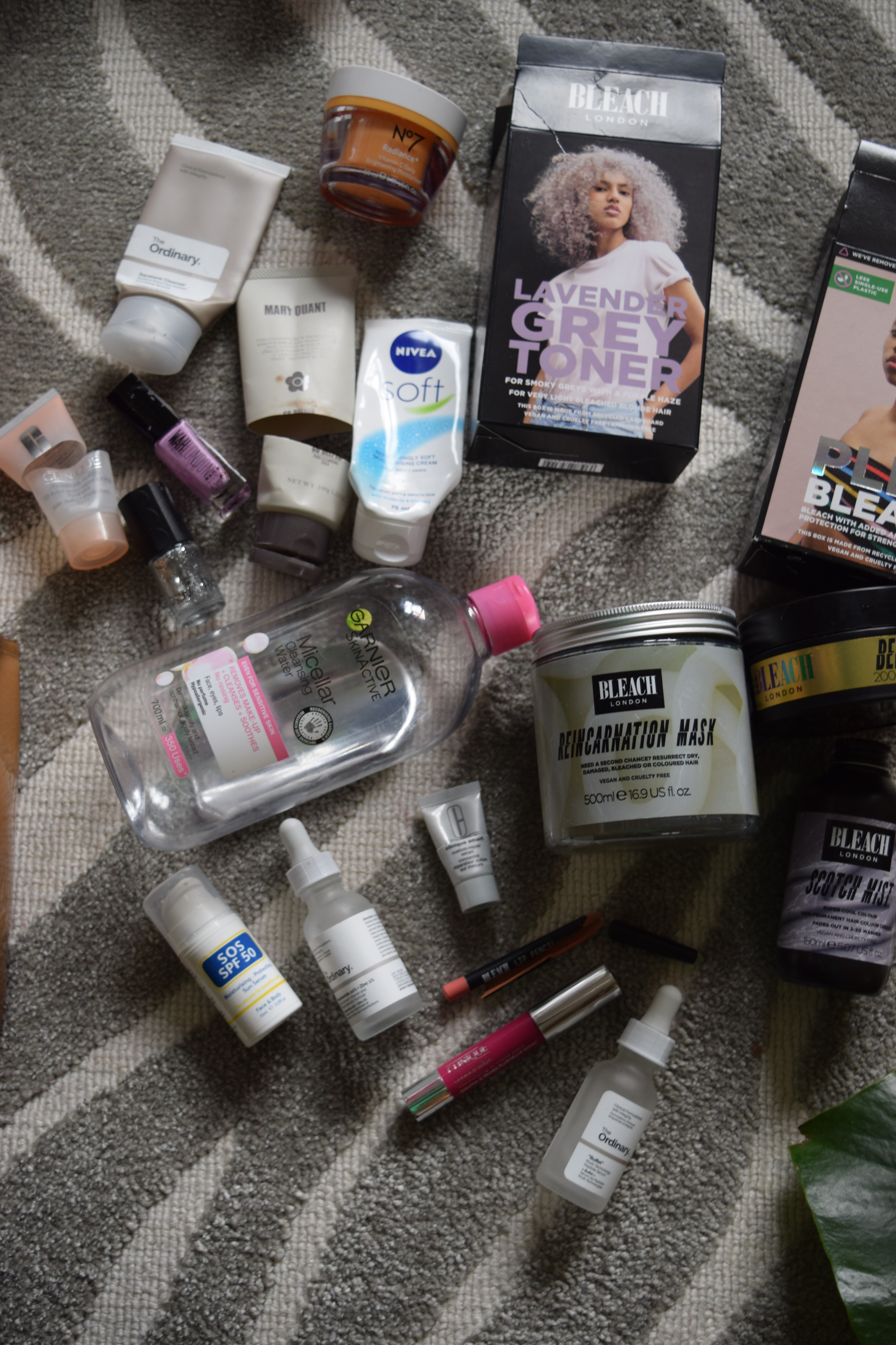 Empty beauty products on a zebra print carpet. Brands include Bleach London, The Ordinary, Mary Quant and Etude House. Some of the tubes have been cut open to get every last bit of product out.