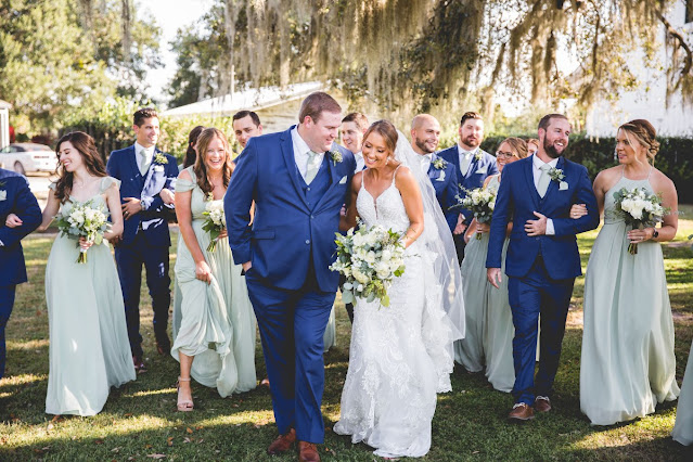 bride and groom walking with bridal party in green and navy