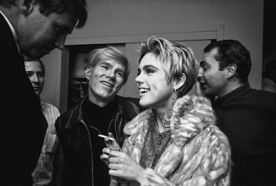 black and white photograph of Andy Warhol swooning at Edie Sedwick at a party in  1965