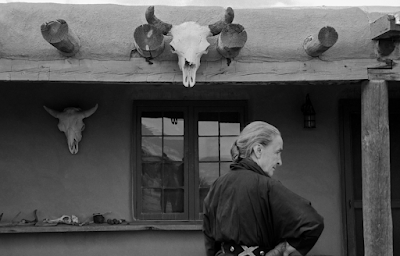 Georgia O'Keeffe on her Abiquiu Portal with cow skull over doorway , NM 1960