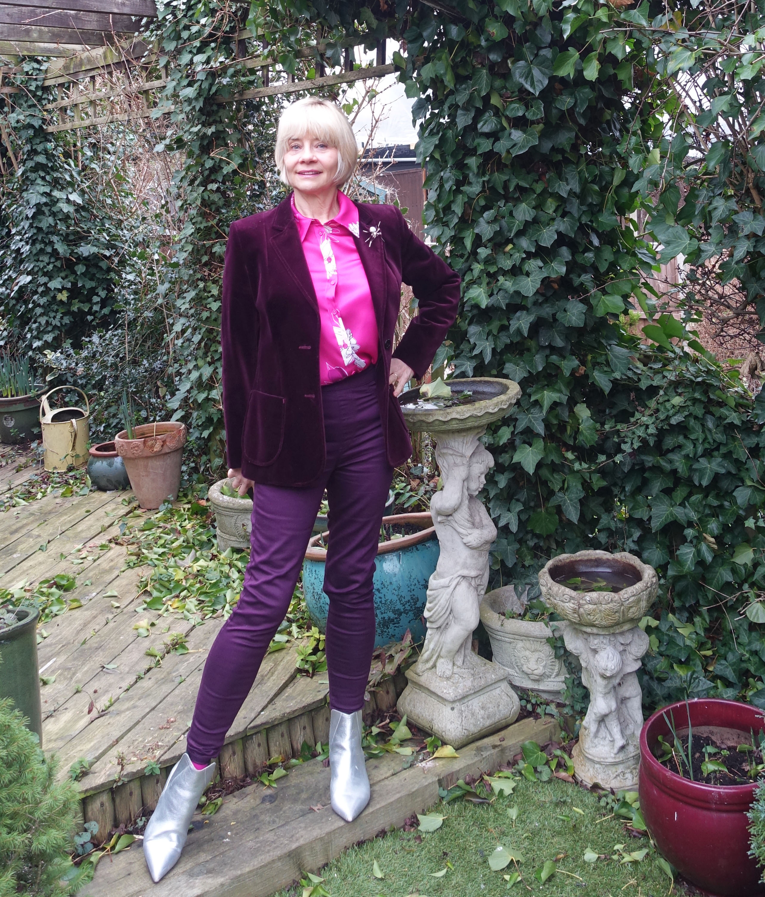 Gail Hanlon from over-50s blog Is This Mutton wearing a burgundy velvet jacket, cerise print blouse, silver ankle boots and burgundy jeggings