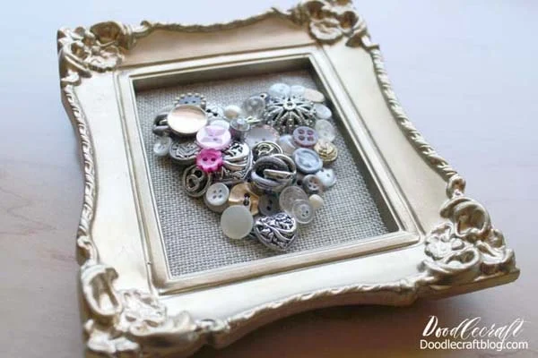I love the combination of old and new.  Rustic and polished.  Those polar opposites make the perfect pairs.  This button art is sparkly and vintage...with rustic burlap and a gilded frame!  It's easy to make and can you believe it just takes 15 minutes!?  Quick crafts are my favorite. Just a few supplies and a little bit of time make this a super darling decoration for Valentine's day or any day of the week. We could all use a little extra love in our life, right!? This heart is perfection.