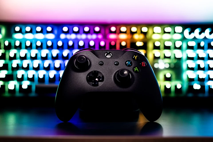 Controle de Xbox em primeiro plano, teclado com luzes LED atrás do controle