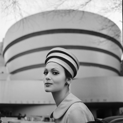 model in architectural hat resembling the Guggenheim Museum in front of the Guggenheim museum in NY, 1960