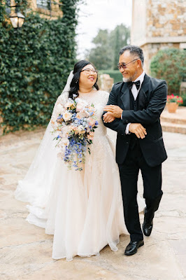 bride walking with dad linking arms are carrying colorful bouquet