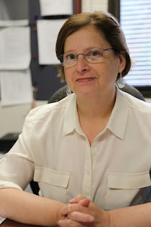 Dr. Ann Scher sits at a desk.