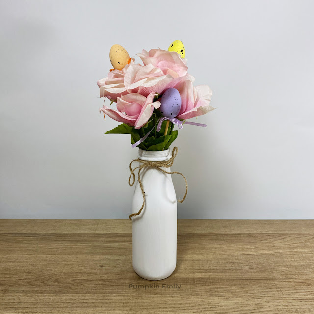 DIY spring and Easter themed flower arrangement in a white bottle.
