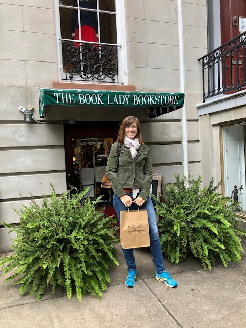 woman holding a shopping bag in front of a bookstore