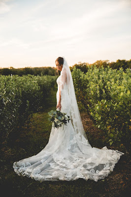 bride in field with greenery holding bouquet