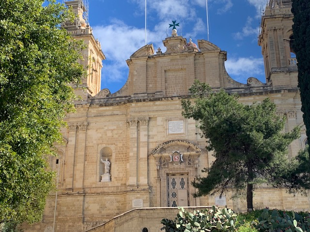 Limestone facade of St Lawrence's Church, surrounded by trees