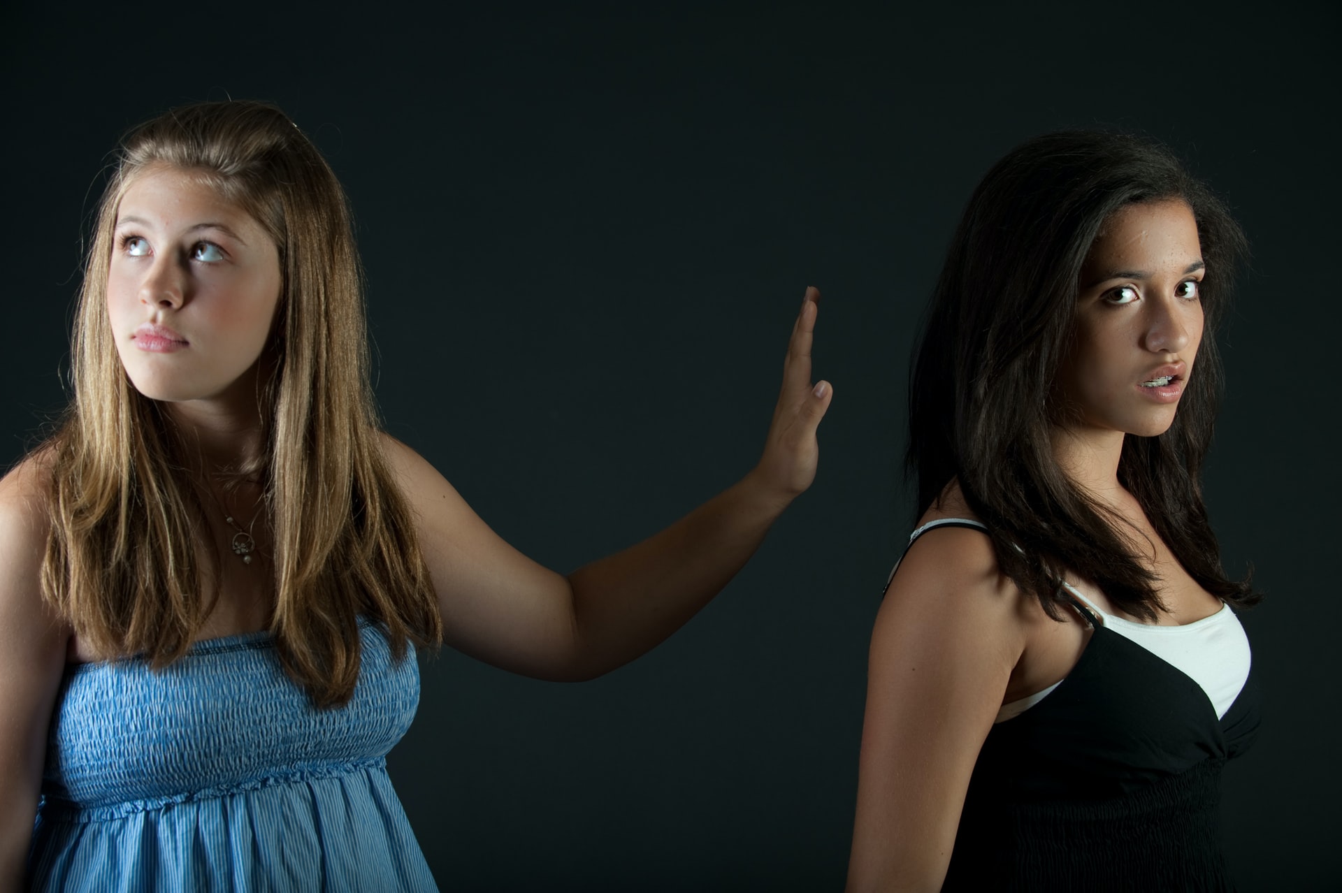 Friends fighting verbally and ignoring each other. Girl in Blue dress and Black dress