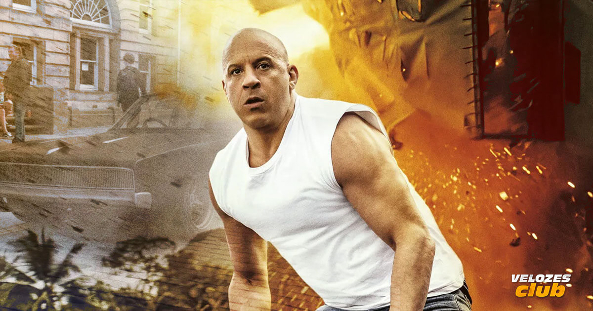 Na imagem vemos o ator Vin Diesel em um olha sério olhando para frente e de fundo há um carro com pessoas e de outro lado há explosão