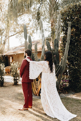 bride in lace dress tapping groom in red suit on the shoulder