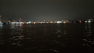 At night with the O2 partially obscured by new development and the cable car traversing the sky