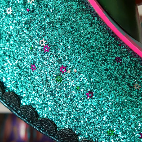 close up of green glitter on shoe with flower shaped pieces in silver and purple