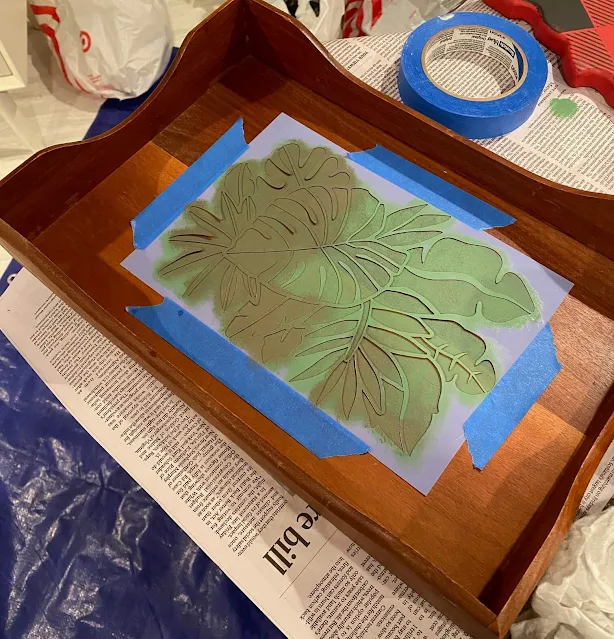 Photo of a tropical leaf stencil being stenciled on a wooden tray.