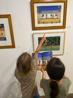 children looking at Frané's art at the exhibition, one pointing to a detail in a piece of art