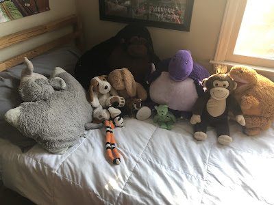 Josh's made bed with all of his stuffed animals displayed on top.