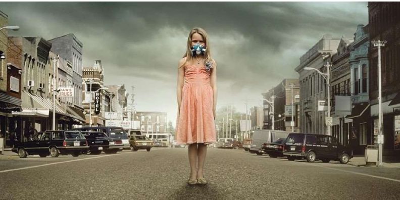 Na imagem podemos ver uma personagem do filme "A Epidemia". Ela está no meio de uma estrada com uma máscara