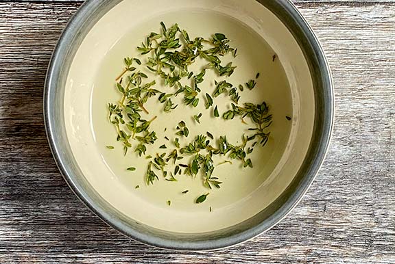 Oil and freshly picked thyme in a bowl.