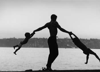 Dancer Jacques D'Amboise swinging his 2 sonse against water background in Seattle, Washingtom