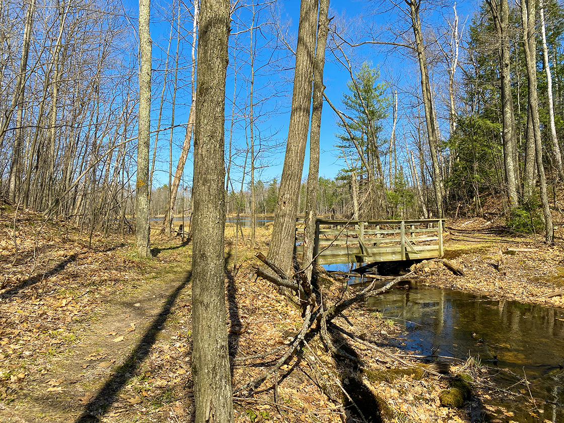 footbridge crossing a stream and lake in distance