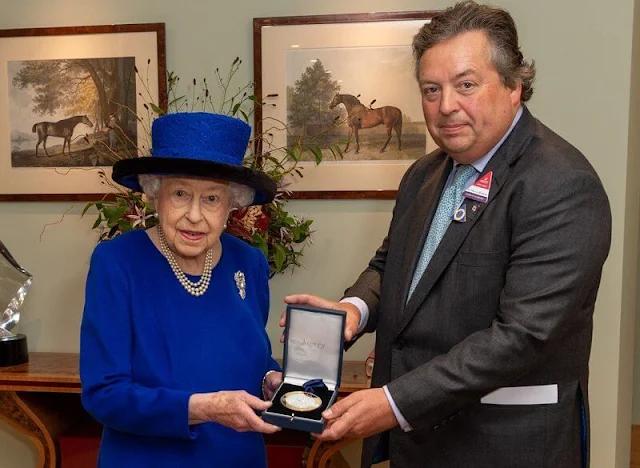 Queen is wearing her vibrant outfit with a typically stylish bag, a pearl necklace and matching earrings, as well as a silver brooch