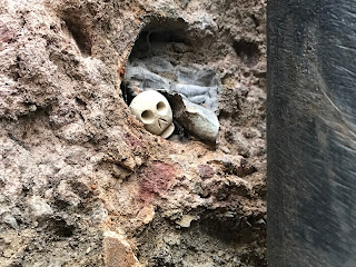 A close up photo showing a small ceramic skull (Skulferatu #62) in a gap in the wall of the Electricity Substation in the Cowgate. Photo by Kevin Nosferatu for the Skulferatu Project.