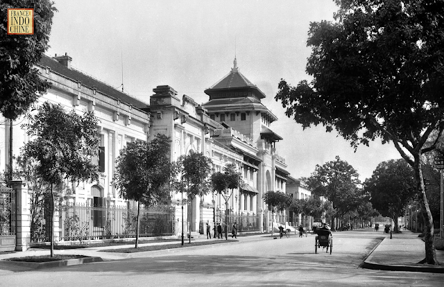 VIỆN ĐẠI HỌC ĐÔNG DƯƠNG Năm xưa: Viện Đại học Đông Dương Ngày này: Khoa Hóa Học - Trường Đại học khoa học tự nhiên Hà Nội (https://www.chemvnu.edu.vn) Địa chỉ: Số 19 phố Lê Thánh Tông, Q. Hoàn Kiếm, Hà Nội Tác phẩm đầu tiên theo phong cách Kiến trúc Đông Dương được xây dựng ở Hà Nội do kiến trúc sư E.Hébrard thiết kế năm 1924 là Toà nhà chính của khu Đại học Đông Dương đã hình thành trước đó. Toạ lạc tại vị trí án ngữ một đại lộ lớn lúc bấy giờ – Boulevard Carreau (phố Lý Thường Kiệt ngày nay), xế phía trước lại có một vườn hoa nhỏ, công trình đã tạo ra một điểm nhấn đô thị nổi bật. Theo thiết kế ban đầu thì đây là một công trình mang phong cách Tân cổ điển với cấu trúc hình khối kiến trúc đăng đối hoàn toàn, mặt bằng không gian theo kiểu chính thống, nhấn mạnh khối sảnh trung tâm, hai phía là giảng đường lớn và thư viện được bố trí trên hai tầng nhà. Tuy nhiên trong quá trình xây dựng, Hébrard đã thay đổi hầu như hoàn toàn hình thức mặt đứng công trình bằng cách đưa vào khá nhiều thành phần kiến trúc Á Đông. Điểm nhấn cho khối trung tâm là bộ mái ngói nhiều lớp theo hình thức bát giác, giữa các lớp mái là các cửa nhỏ trang trí hoa văn bên cạnh hàng con sơn đỡ mái theo kiểu Trung Hoa cổ. Bộ mái ngói còn được sử dụng như một hình thức kết thúc phương đứng ở hai cánh nhà, ở tiền sảnh phía sau nhà. Các cửa sổ cũng được che bởi các ô văng chéo dán ngói. Hệ thống cửa của công trình cũng được kiến trúc sư – tác giả hết sức lưu tâm. Cửa ra vào chính là một cửa dạng vòm có độ cao tương đương hai tầng nhà được trang trí bằng kính và kim loại theo phong cách Art Nouveau, không chỉ làm đẹp cho công trình khi nhìn từ ngoài vào mà làm tăng tính thẩm mỹ cho khu đại sảnh khi nhìn từ trong ra. Các cửa sổ mở rộng kiểu cuốn vòm ở tầng 1 được nhóm thành hai cửa sổ hình chữ nhật ở tầng 2 cùng các cửa nhỏ trên mái sảnh tạo ra sự biến hoá nhưng vẫn mang tính thống nhất cao. Các họa tiết trang trí Á Đông được sử dụng rộng rãi, mặt tiền tòa nhà được trang trí bởi các hình hoa văn chữ triện, hình bát giác rất phổ biến trong kiến trúc đình chùa Việt cổ, các hình này còn được nhắc lại trên các diềm mái càng làm tôn nổi tính bản địa của công trình. Nhắc tới Đại học Đông Dương thì chúng ta không thể bỏ qua phần nội thất của công trình. Nếu mặt ngoài toà nhà mang dáng vẻ Á Đông thì phần nội thất lại chủ yếu theo tinh thần kinh viện Châu Âu. Chính sảnh được phủ bởi một bộ vòm hai lớp với các hàng cột, các hoạ tiết trang trí kiểu Tân cổ điển. Các không gian lớn và thoáng đãng đặc trưng của các đại học lớn ở Pháp thời bấy giờ. Đặc biệt là trong giảng đường chính có bức tranh tường lớn nhất Việt Nam do hoạ sĩ Victor Tardieu thực hiện, mô tả cuộc sống của người Hà Nội đầu thế kỷ 20 với sự hiện diện của 200 nhân vật đại diện cho xã hội thời bấy giờ. Công trình Đại học Đông Dương có thể được coi là thử nghiệm đầu tiên của E. Hébrard theo phong cách kết hợp nên còn thiếu sự ăn nhập giữa nội – ngoại thất công trình. Tuy nhiên với hình khối được tổ chức chuẩn mực theo tinh thần cổ điển kết hợp với các hình thức trang trí mặt đứng theo tinh thần Á Đông, toà nhà chính Đại học Đông Dương có thể coi là công trình tiên phong của trường phái Kiến trúc Đông Dương, một sự kết hợp thành công bước đầu giữa kiến trúc nói riêng và văn hoá Phương Đông và Phương Tây nói chung ở Hà Nội