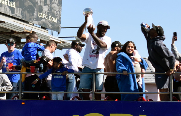 Leonard Floyd hoists up the Lombardi Trophy during the Los Angeles Rams' Super Bowl LVI championship parade...on February 16, 2022. Defensive tackle Aaron Donald is the shirtless dude behind him.