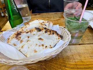Paratha in a basket next to my drink with mint leaves in it.
