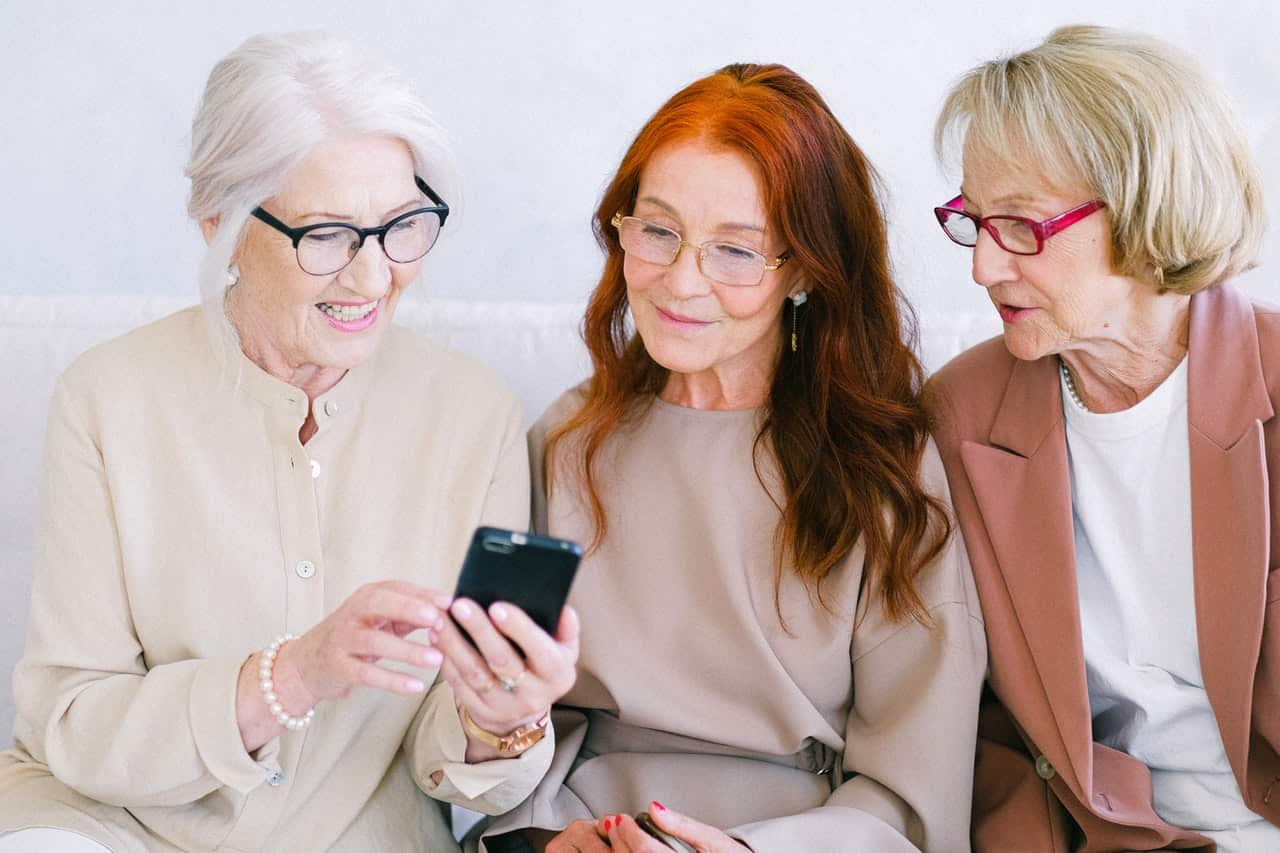 Three senior happy women watching a smartphone