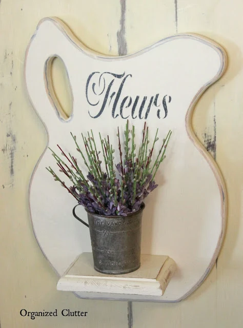 Photo of a pitcher plaque with small shelf and French stenciling.