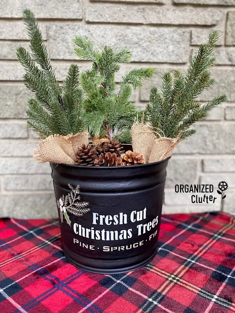 Photo of a metal bucket upcycled with Christmas stencils from Old Sign Stencils, and a decor transfer from Redesign with Prima.