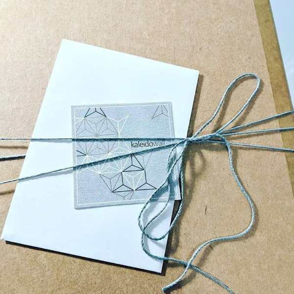 brown paper box tied with grey twine displays Kaleidowall business card
