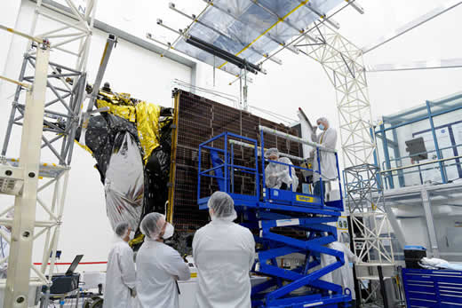 Antes de um teste de implantação em uma sala limpa na JPL, os engenheiros examinam uma das duas matrizes solares da Psyche.