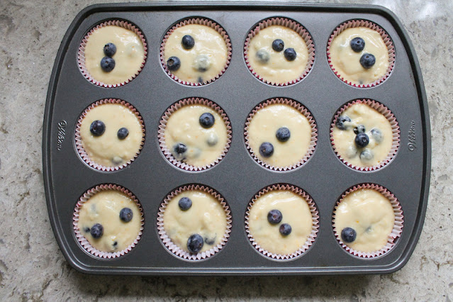 Muffin cups filled with battered and topped with a few extra blueberries