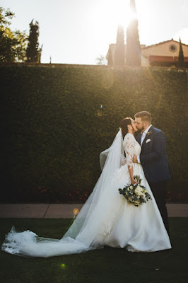 bride and groom kissing in front of hedge wall