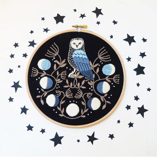 A beautiful embroidered blue owl with moon phases below them