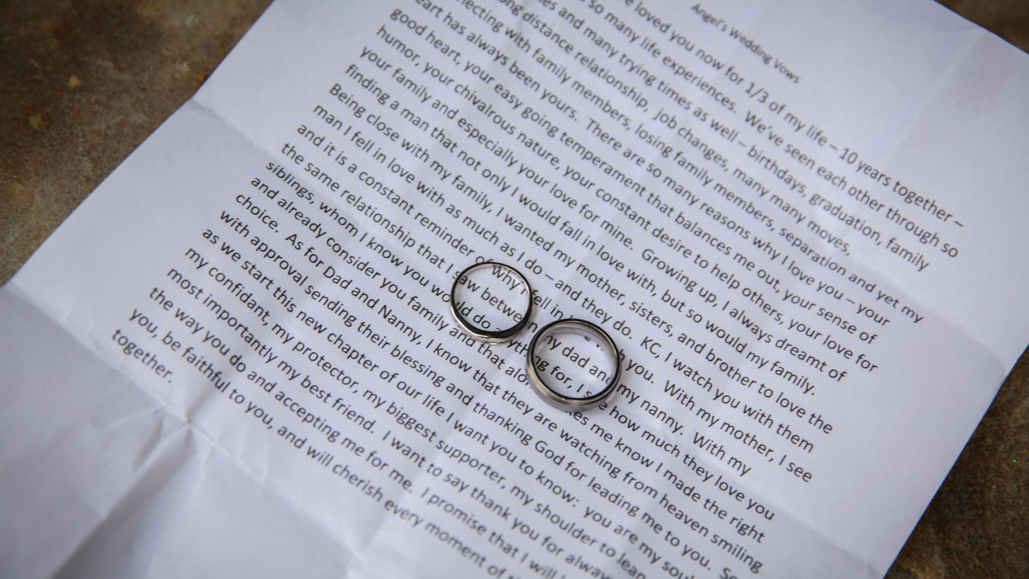 A page of paper with wedding vows typed on it. Two rings sit on top.