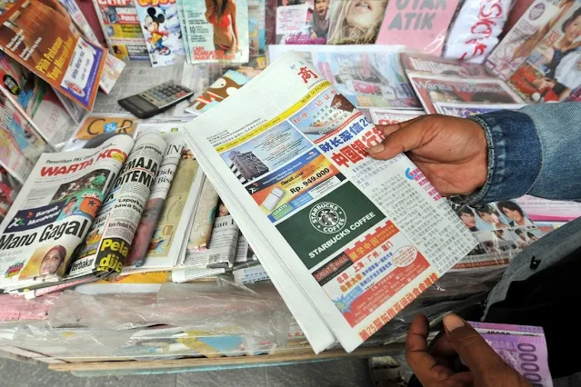 Cover Image Attribute: A vendor holds a copy of the ‘Indonesia Shangbao’ newspaper in Jakarta. / Photo Source: AFP