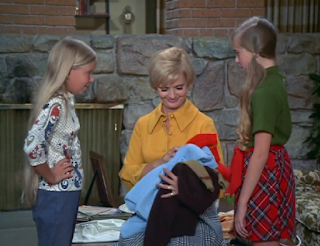 Jan and Marcia Brady give Carol their old clothes.