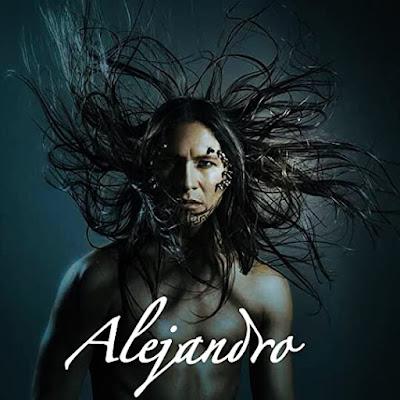 Dramatic and dark image of an indigenous man with his long dark hair blowing the caption reads Alejandro