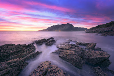 cala de rocas con un colorido y calido amanecer