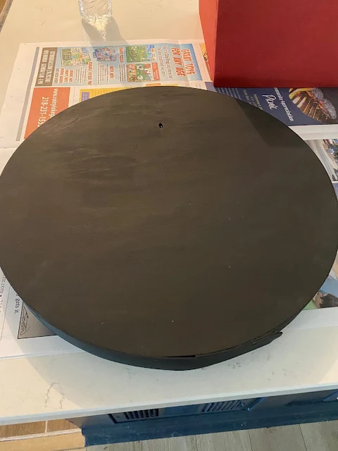 Photo of a round wooden box being painted black.