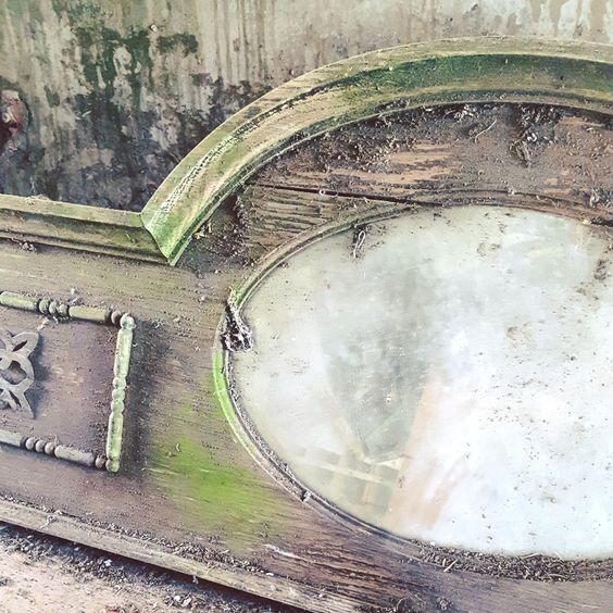 An image of part of a mirror set into a wooden lintel lying on the ground. Taken by Lisa Shambrook.