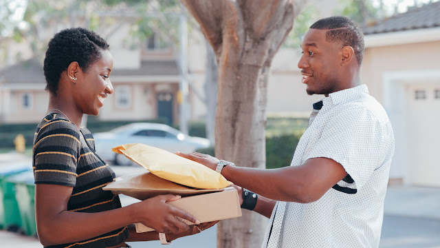 A lady receiving packages from a delivery man.