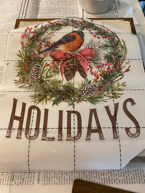 Photo of a Christmas decor transfer being applied to a slatted wooden photo holder.